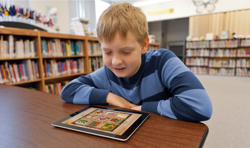 Acessibilidade: criança sorridente em uma biblioteca utilizando um iPad para aprendizado.