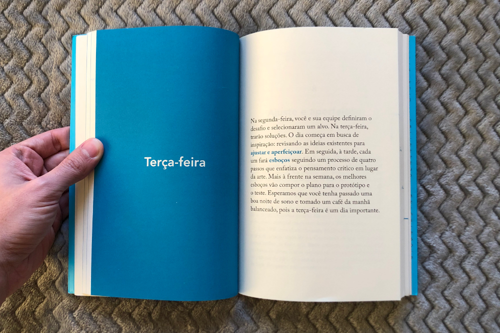 Livro Sprint aberto ao meio, com uma página à esquerda toda em azul e escrito no centro terça-feira, mostrando o título do capítulo e à direita um resumo do que será abordado