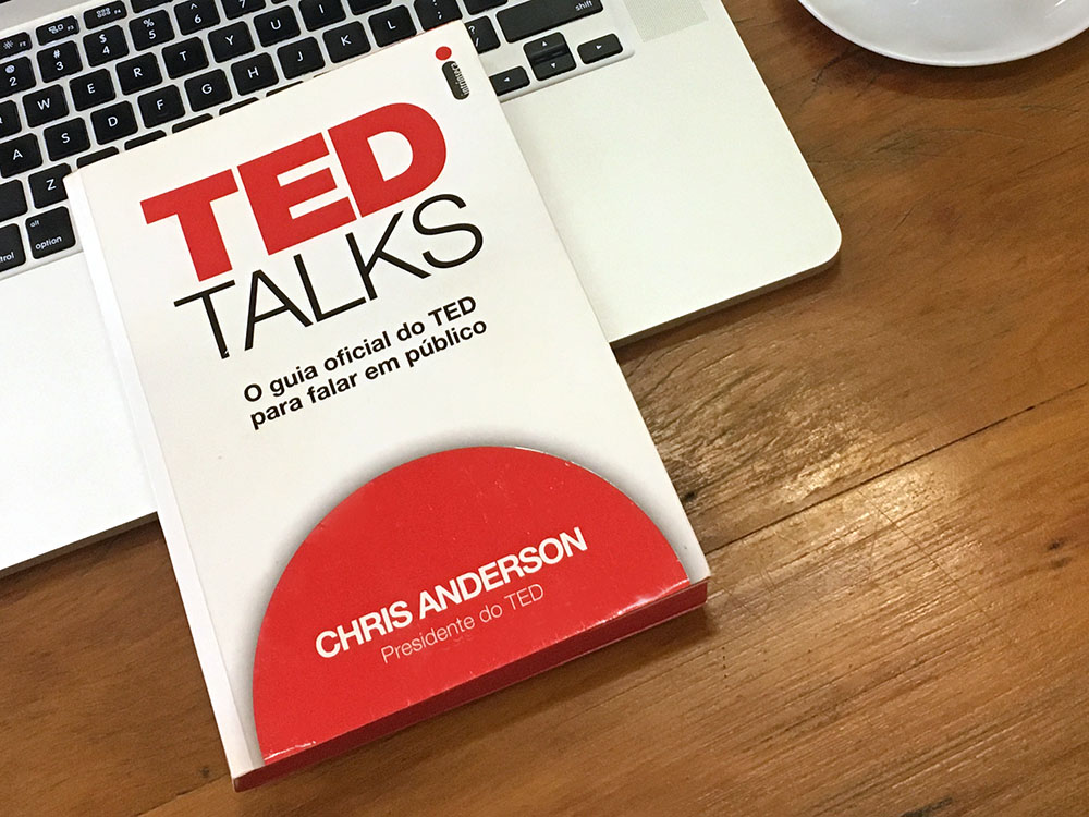 Livro TED Talks sobre uma mesa com um MacBook e uma xícara de café