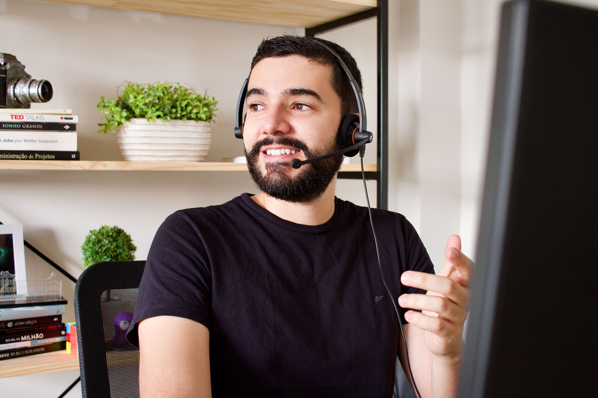 Thiago Nascimento, autor do site, sentado diante de um computador, utilizando o headset da Sennheiser SC-60 enquanto olha para o lado e sorri durante chamada