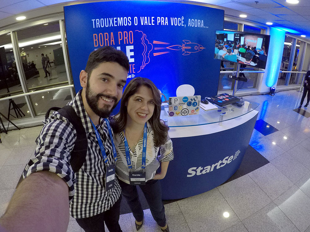 Thiago Nascimento e Francine Hudson de frente a balcão da StartSe utilizado no credenciamento dos participantes