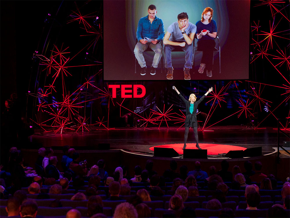Livro TED Talks sobre uma mesa com um MacBook e uma xícara de café